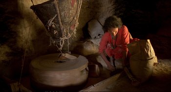 Movie still from “Powaqqatsi” (1988), directed by Godfrey Reggio – A woman in a red shirt is working in a cave; Wide shot, High angle