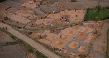 Movie still from “Powaqqatsi” (1988), directed by Godfrey Reggio – People are working in a field of sand; Extreme Wide shot, Overhead angle