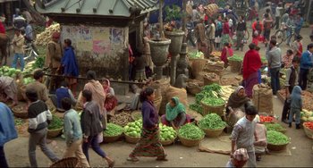 Movie still from “Powaqqatsi” (1988), directed by Godfrey Reggio – A group of people walking down a street with baskets full of vegetables; Extreme Wide shot, High angle