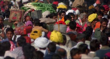 Movie still from “Powaqqatsi” (1988), directed by Godfrey Reggio – A large group of people walking down a street; Wide shot, High angle