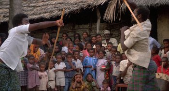 Movie still from “Powaqqatsi” (1988), directed by Godfrey Reggio – A group of people standing in front of a building; Wide shot, Over the shoulder angle