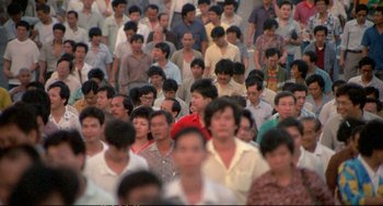 Movie still from “Powaqqatsi” (1988), directed by Godfrey Reggio – A large group of people standing in the street; Extreme Wide shot, High angle