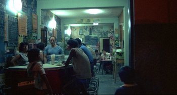 Movie still from “Powaqqatsi” (1988), directed by Godfrey Reggio – A group of people sitting at a table in a restaurant; Wide shot, High angle