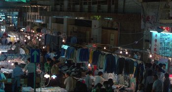 Movie still from “Powaqqatsi” (1988), directed by Godfrey Reggio – A group of people are shopping at an outdoor market; Extreme Wide shot, High angle