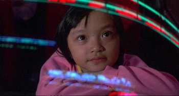 Movie still from “Powaqqatsi” (1988), directed by Godfrey Reggio – A little girl sitting in front of some lights; Close Up shot, High angle