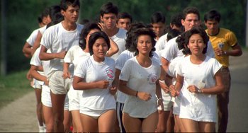Movie still from “Powaqqatsi” (1988), directed by Godfrey Reggio – A large group of people in white shirts and shorts running together; Wide shot, High angle