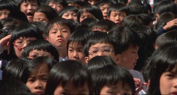 Movie still from “Powaqqatsi” (1988), directed by Godfrey Reggio – A large group of people with very long black hair; Close Up shot, High angle