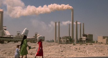 Movie still from “Powaqqatsi” (1988), directed by Godfrey Reggio – Two women walk through the desert carrying bags of food; Extreme Wide shot, Low angle