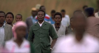 Movie still from “Powaqqatsi” (1988), directed by Godfrey Reggio – A man and a woman are walking in a crowd; Medium shot, Low angle