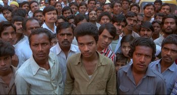 Movie still from “Powaqqatsi” (1988), directed by Godfrey Reggio – A large group of men standing in front of each other; Medium shot, High angle