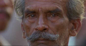 Movie still from “Powaqqatsi” (1988), directed by Godfrey Reggio – An old man with a beard and a mustache; Extreme Close Up shot, High angle