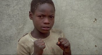 Movie still from “Powaqqatsi” (1988), directed by Godfrey Reggio – A young boy is posing for a picture; Close Up shot, High angle
