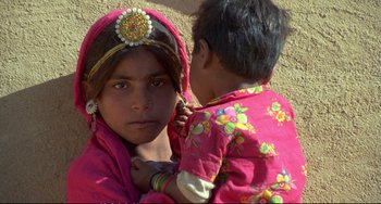 Movie still from “Powaqqatsi” (1988), directed by Godfrey Reggio – A young girl in a pink dress and a young boy; Close Up shot, High angle