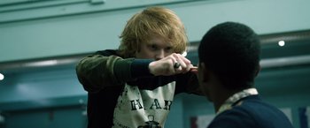 Movie still from “Power Rangers” (2017), directed by Dean Israelite – A man with a red hair pointing a knife at another man's face; Medium shot, Over the shoulder angle