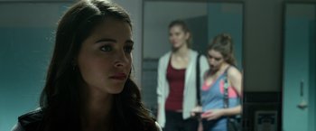 Movie still from “Power Rangers” (2017), directed by Dean Israelite – A woman looking at the camera while standing next to two other women; Close Up shot, Over the shoulder angle