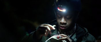 Movie still from “Power Rangers” (2017), directed by Dean Israelite – A young man wearing a headlamp looking down at a wire; Close Up shot, Low angle