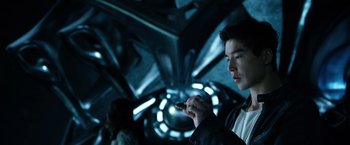 Movie still from “Power Rangers” (2017), directed by Dean Israelite – A man holding a cell phone while standing in a dark room; Close Up shot, Over the shoulder angle