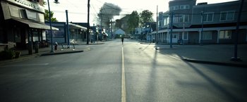 Movie still from “Power Rangers” (2017), directed by Dean Israelite – A person riding a bike down the middle of a street; Extreme Wide shot, Low angle