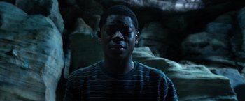 Movie still from “Power Rangers” (2017), directed by Dean Israelite – A young man in a striped shirt in front of some rocks; Close Up shot, Low angle