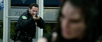 Movie still from “Power Rangers” (2017), directed by Dean Israelite – A man holding a gun in front of a woman; Medium shot, Over the shoulder angle