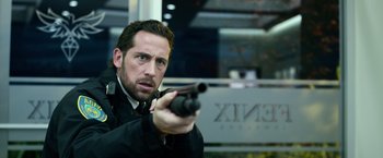 Movie still from “Power Rangers” (2017), directed by Dean Israelite – A man in a black jacket and tie holding a gun; Close Up shot, Low angle