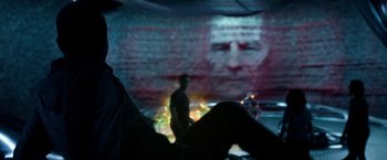Movie still from “Power Rangers” (2017), directed by Dean Israelite – A man standing in front of a wall that has a picture of a man on it on it; Close Up shot, Over the shoulder angle