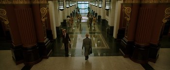 Movie still from “Predestination” (2014), directed by Michael Spierig – A group of people walking down a hall way; Extreme Wide shot, High angle