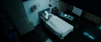 Movie still from “Predestination” (2014), directed by Michael Spierig – A dummy is laying on a bed in a hospital room; Medium shot, High angle