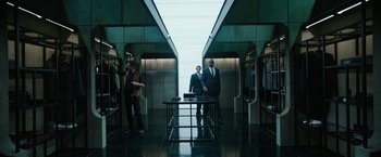 Movie still from “Predestination” (2014), directed by Michael Spierig – Two men in business suits standing next to each other in an elevator; Wide shot, Over the shoulder angle