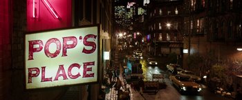 Movie still from “Predestination” (2014), directed by Michael Spierig – People walking down a street at night near a street sign; Wide shot, High angle