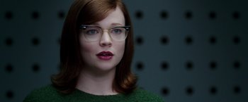 Movie still from “Predestination” (2014), directed by Michael Spierig – A person wearing glasses and a green sweater; Close Up shot, Over the shoulder angle