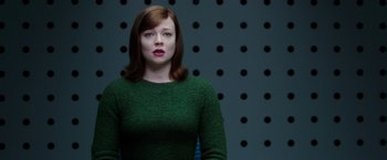 Movie still from “Predestination” (2014), directed by Michael Spierig – A woman in a green sweater standing in front of a wall; Medium shot, Low angle