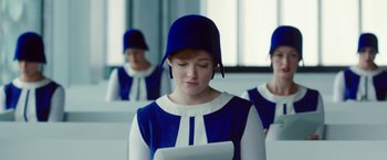 Movie still from “Predestination” (2014), directed by Michael Spierig – A woman wearing a blue hat looking down at a laptop; Medium shot, Over the shoulder angle