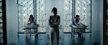 Movie still from “Predestination” (2014), directed by Michael Spierig – A woman standing next to two other women in a room; Medium shot, Low angle