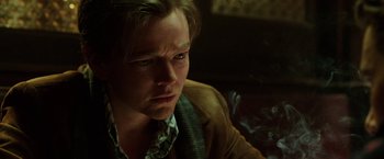 Movie still from “Predestination” (2014), directed by Michael Spierig – A person sitting down with smoke coming out of his mouth; Close Up shot, Low angle