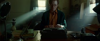 Movie still from “Predestination” (2014), directed by Michael Spierig – A person sitting at a table typing on a typewriter; Medium shot, Low angle