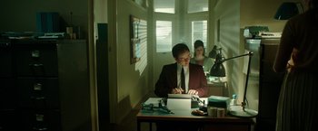 Movie still from “Predestination” (2014), directed by Michael Spierig – A man sitting at a table with a laptop; Medium shot, Low angle