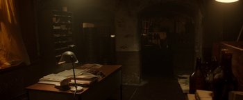 Movie still from “Predestination” (2014), directed by Michael Spierig – A dimly - lit room with a desk and a lamp; Wide shot, High angle