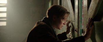 Movie still from “Predestination” (2014), directed by Michael Spierig – A woman leaning against a window sill looking out the window; Close Up shot, Over the shoulder angle
