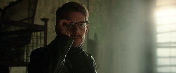 Movie still from “Predestination” (2014), directed by Michael Spierig – A man with a beard and glasses is looking at the camera; Close Up shot, Over the shoulder angle