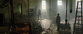 Movie still from “Predestination” (2014), directed by Michael Spierig – Two people in a room with a lot of furniture; Wide shot, Low angle