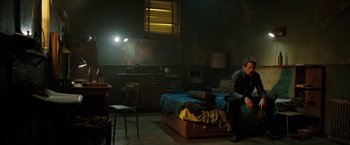 Movie still from “Predestination” (2014), directed by Michael Spierig – A man sitting on a bed in a dark room; Wide shot, High angle