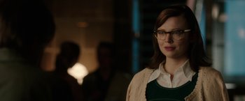 Movie still from “Predestination” (2014), directed by Michael Spierig – A woman wearing glasses standing in front of a lamp; Close Up shot, Over the shoulder angle