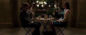 Movie still from “Predestination” (2014), directed by Michael Spierig – A group of people sitting at a table with cups; Wide shot, Over the shoulder angle