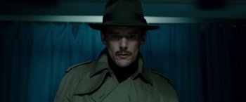 Movie still from “Predestination” (2014), directed by Michael Spierig – A man wearing a hat and a trench coat; Close Up shot, Low angle