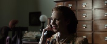 Movie still from “Predestination” (2014), directed by Michael Spierig – A woman talking on a phone while sitting in a room; Close Up shot, Over the shoulder angle