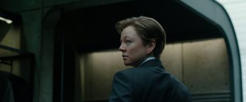 Movie still from “Predestination” (2014), directed by Michael Spierig – A woman in a suit looking to her left; Close Up shot, Over the shoulder angle