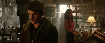 Movie still from “Predestination” (2014), directed by Michael Spierig – A man and a woman standing in a dimly - lit room; Medium shot, Low angle