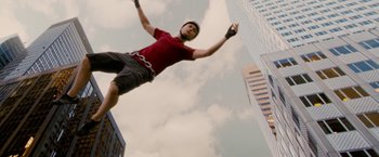 Movie still from “Premium Rush” (2012), directed by David Koepp – A man flying through the air while holding onto a chain; Wide shot, Low angle