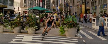 Movie still from “Premium Rush” (2012), directed by David Koepp – A man riding a bike down the middle of a street; Wide shot, High angle